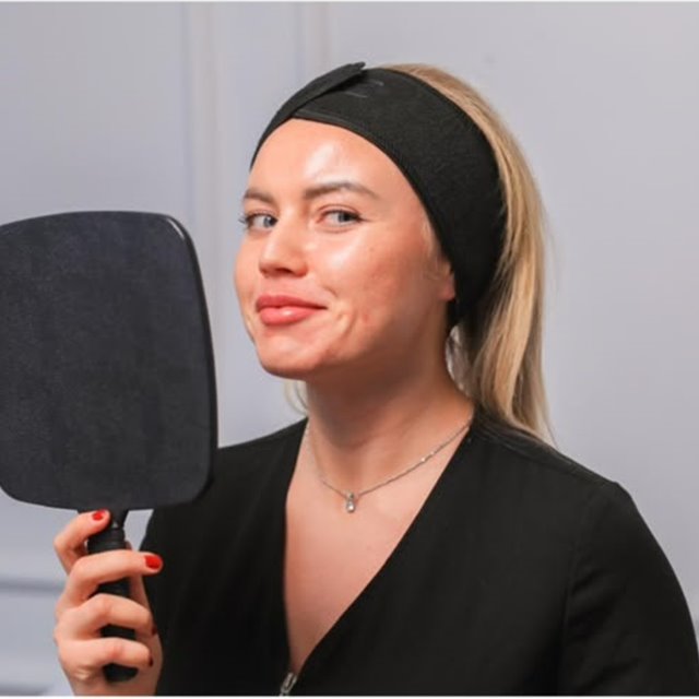Client holding the mirror after her skin treatment at Face Code Aesthetic, Putney SW15